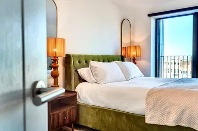 a bedroom with a bed with a green headboard and a window at Luxury City Escape - Brand New Stylish 2 Bedroom Apartment with Parking in Liverpool