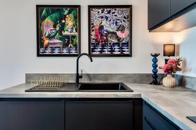 a kitchen with a sink and two paintings on the wall at Luxury City Escape - Brand New Stylish 2 Bedroom Apartment with Parking in Liverpool