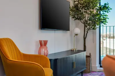 a living room with two chairs and a tv on a wall at Luxury City Escape - Brand New Stylish 2 Bedroom Apartment with Parking in Liverpool