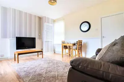 a living room with a couch and a clock on the wall at Travellers Economic Stays in Orrell Park in Liverpool