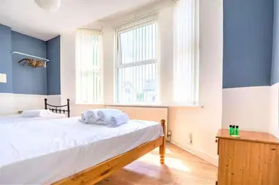 a bedroom with a bed with blue walls and a window at Travellers Economic Stays in Orrell Park in Liverpool