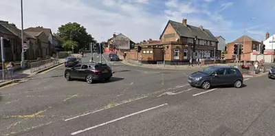 two cars driving down a street in a town at Travellers Economic Stays in Orrell Park in Liverpool