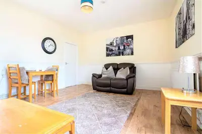 a living room with a black leather couch and a table at Travellers Economic Stays in Orrell Park in Liverpool