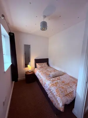 a bedroom with a bed and a mirror and a lamp at Beautiful park view town house in Wigan