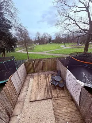 a wooden deck with a bench next to a pond at Beautiful park view town house in Wigan
