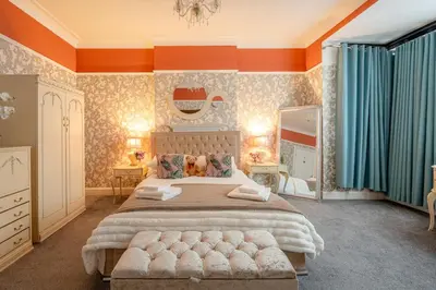 a bedroom with a large bed with an orange wall at Southport Rabbit Retreat in Southport