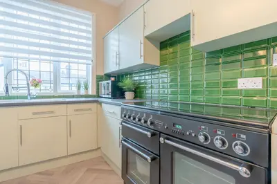 a kitchen with a stove and green tiles at Southport Rabbit Retreat in Southport