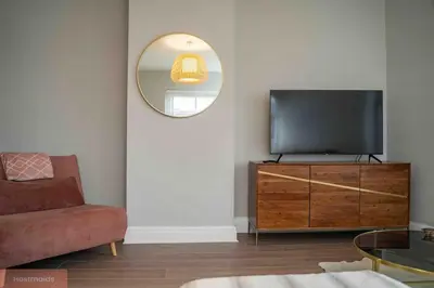 a living room with a television on a dresser with a mirror at Apartment near Blackpool Central & Pleasure Beach in Blackpool