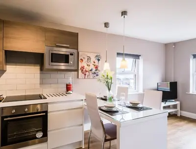 a kitchen with a table with chairs and a counter top at Fishergate Apartments in Preston