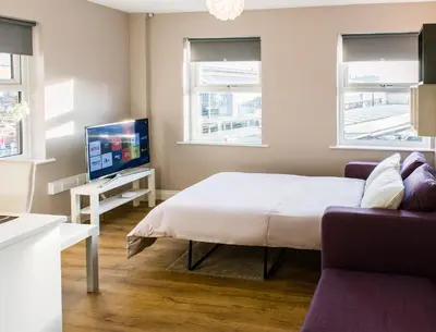 a bedroom with a bed and a tv and a couch at Fishergate Apartments in Preston