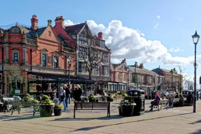 a city street with people sitting on benches and buildings at Fairhaven View Apartments - Lytham St Annes in Lytham St Annes