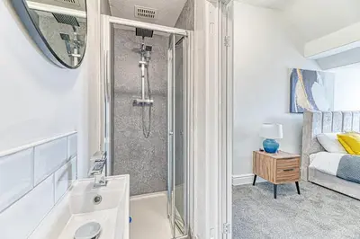 a bathroom with a shower and a sink and a bed at Fairhaven View Apartments - Lytham St Annes in Lytham St Annes