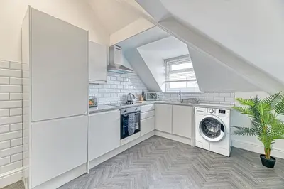 a kitchen with white cabinets and a washer and dryer at Fairhaven View Apartments - Lytham St Annes in Lytham St Annes