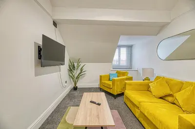 a living room with a yellow couch and a table at Fairhaven View Apartments - Lytham St Annes in Lytham St Annes