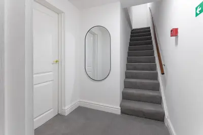 a hallway with a stairway with a mirror at Flatzy - City Centre Mansion 2, Sleeps 22, 4 Baths in Liverpool