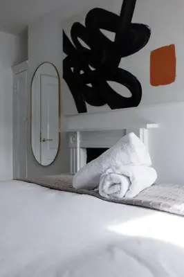 a towel sitting on a bed next to a mirror at Flatzy - City Centre Mansion 2, Sleeps 22, 4 Baths in Liverpool