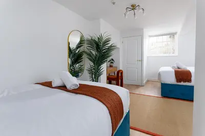 a bedroom with two beds and a plant at Flatzy - City Centre Mansion 2, Sleeps 22, 4 Baths in Liverpool