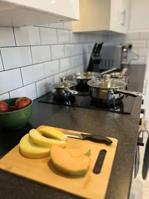 a cutting board with bananas and apples on a kitchen counter at Ideal 3 bed pay-as-you-stay home in Wigan sleeps 6 in Wigan