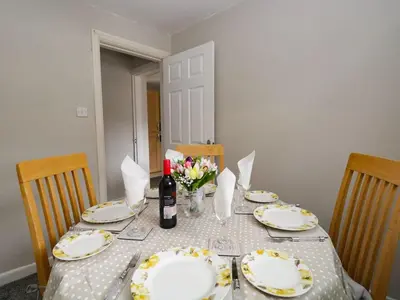 a table with plates and a bottle of wine and flowers at The Old Surgery in Grange Over Sands