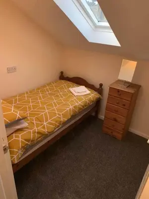 a bedroom with a bed and a lamp and a dresser at The Old Surgery in Grange Over Sands