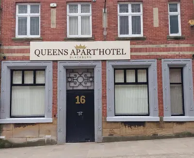 a brick building with a black door in front at Queens Hotel in Blackburn