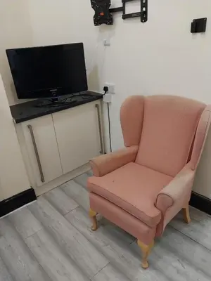 a living room with a chair and a television at Queens Hotel in Blackburn
