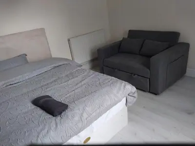 a bedroom with a bed and a couch and a chair at Queens Hotel in Blackburn
