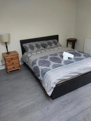 a bedroom with a large bed and a night stand at Queens Hotel in Blackburn