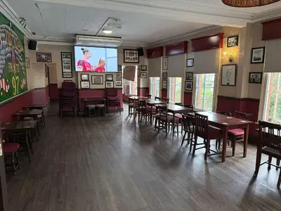 a dining room with tables and chairs and a screen at Twelfth Man Accommodation part of The Twelfth Man Public House in Liverpool