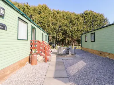 a couple of green buildings with chairs between them at Lodge 1 in Carnforth