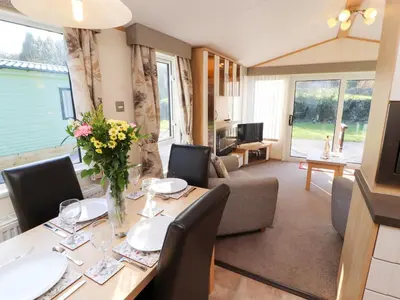 a dining room with a table and a living room at Lodge 2 in Carnforth