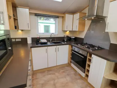 a kitchen with white cabinets and a stove top oven at Lodge 2 in Carnforth