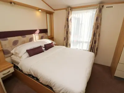 a bedroom with a large bed and a window at Lodge 2 in Carnforth