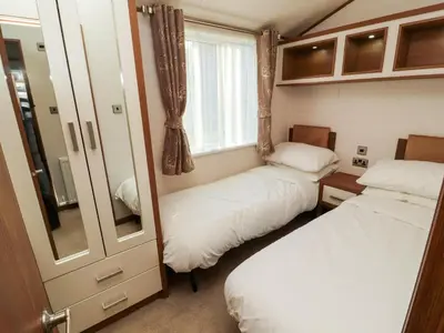 a small room with two beds and a mirror at Lodge 4 in Carnforth