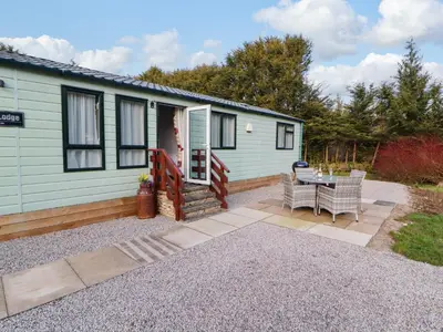 a small house with a patio and a table at Lodge 4 in Carnforth