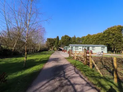 a dirt road leading to a house with a fence at Lodge 4 in Carnforth