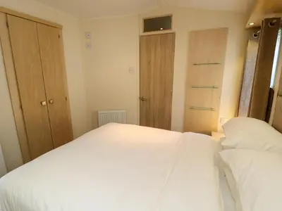 a bedroom with two white beds and wooden cabinets at Lodge 3 in Carnforth