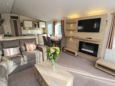 a living room with a couch and a television and a table at Lodge 3 in Carnforth
