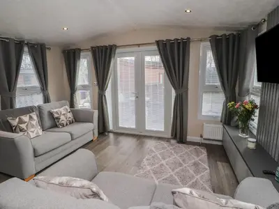a living room with a couch and windows at 24 Sherwood in Carnforth