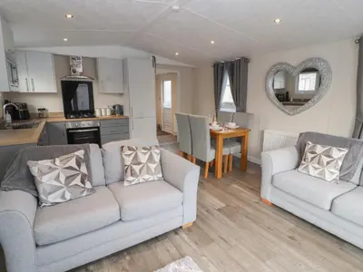 a living room with two couches and a kitchen at 24 Sherwood in Carnforth