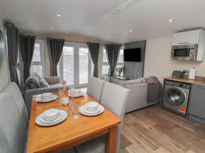a living room with a dining table and a kitchen at 24 Sherwood in Carnforth