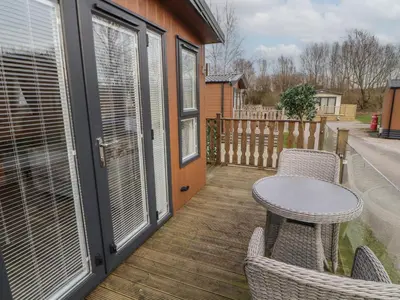 a patio with a table and chairs on a deck at 24 Sherwood in Carnforth