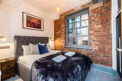 a brick walled bedroom with a bed and a window at Bands Warehouse I in Liverpool