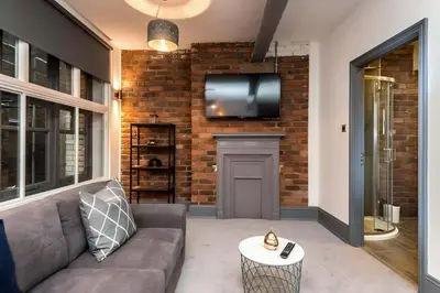 a living room with a couch and a tv on a brick wall at Bands Warehouse I in Liverpool