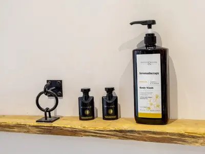 a bottle of soap on a wooden shelf with three candles at Lovely 2 Bed With Pool Table Ulverston - Pass the Keys in Ulverston