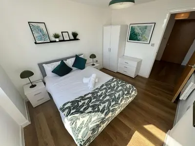 a bedroom with a bed with white sheets and blue pillows at Two Bedroom City View Apartment Liverpool by StaySavvy Accommodation in Liverpool