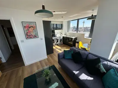 a living room with a couch and a view of a kitchen at Two Bedroom City View Apartment Liverpool by StaySavvy Accommodation in Liverpool