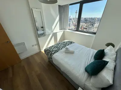 a bedroom with a bed with pillows and a window at Two Bedroom City View Apartment Liverpool by StaySavvy Accommodation in Liverpool