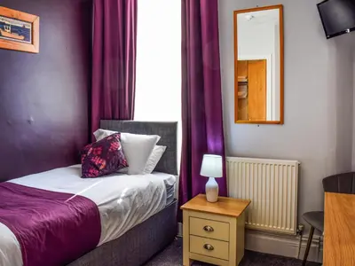 a small bedroom with a bed with purple curtains at The Sandcastle in Blackpool