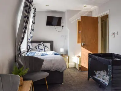 a bedroom with a bed and a chair and a television at The Sandcastle in Blackpool